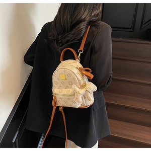 Detailed view of mini printed backpack with brown monogram and puppy charm on model
