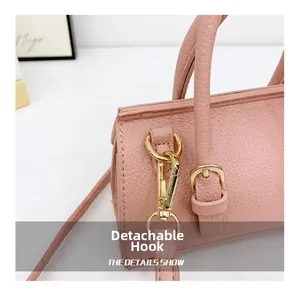 Close-up of pink leather handbag with detachable gold metal hook and buckle strap detail
