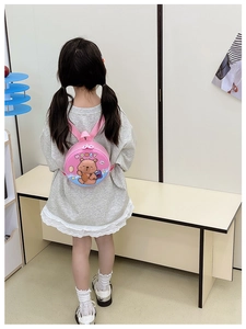 Rear view of a young girl wearing a mini round pink hardshell backpack with a bear