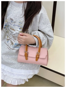 Detail of pink lychee leather toddler handbag with brown handles and golden buckles