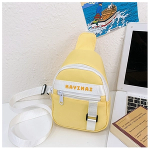 Detail of a bright yellow kids crossbody bag with KAYINAI lettering on a white desk