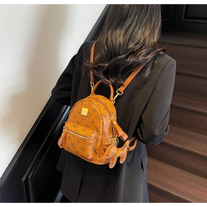 Detail of printed small backpack with puppy charm on model in modern stair setting
