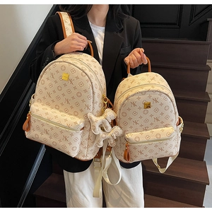 Detail of fashion backpack featuring stylish letter prints and a cute dog charm accessory