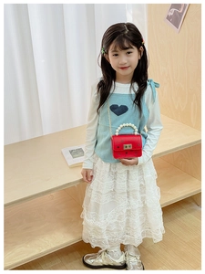 Dettaglio mini borsa rossa da bambina con manico di perle, chiusura in metallo e catena