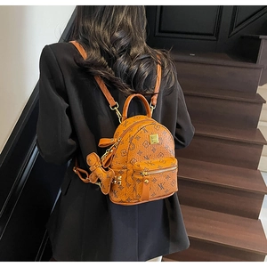 Detail view of brown monogram backpack with mini bear pendant and gold hardware