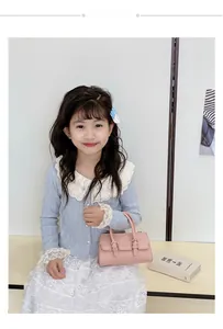 Pink mini crossbody bag for kids featuring a gold buckle with a lace outfit