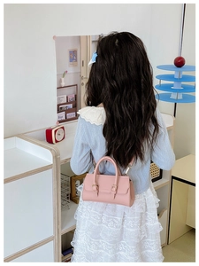 Pink mini children's handbag with litchi texture and metal buckle detail on a kid's back