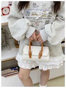 Close-up of white lychee leather mini handbag with brown handle and metal buckle details