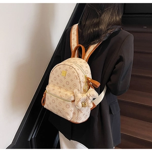 Detail of a beige letter-print backpack with a cute dog charm and leather handle