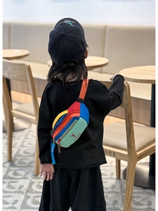 Rear view of a child wearing a colorful patchwork chest bag with deer logo in a cafe