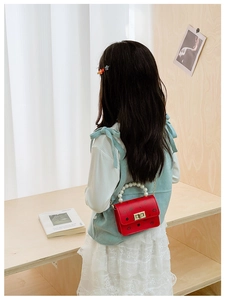 Dettaglio della mini borsa rossa per bambine con manico di perle e tracolla a catena