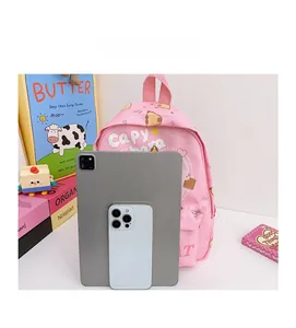 Pink kids backpack with cute Capybara print shown next to a tablet for size comparison