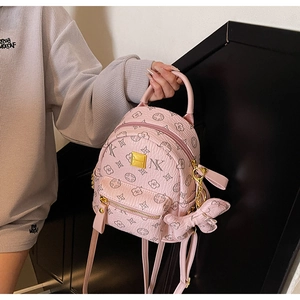 Detailed close-up of pink mini backpack with floral monogram pattern and bow charm accessory