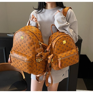 Close-up of brown monogram backpacks in two sizes with gold hardware and pony charms