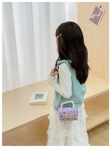 Dettaglio mini borsa viola da bambina con manico di perle e catena dorata su modella