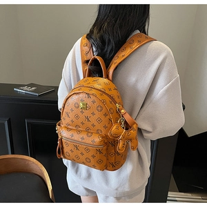 Fashionable brown backpack with logo print and puppy charm worn on model's back