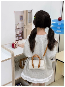 Detail showing white lychee texture leather girl's handbag with brown strap and handle