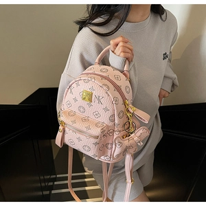 Detail view of pink mini backpack featuring monogram prints and a cute bear charm