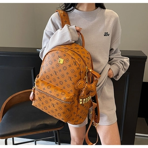 Close-up of brown monogram backpack with golden studs and a dog-shaped keychain