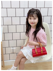 Close-up of a red lychee textured PU leather mini handbag held by a little girl