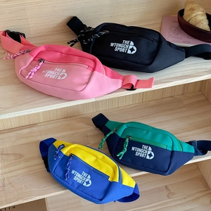 Détail de sacs banane en toile multicolore avec sangles réglables sur étagère bois