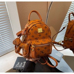Detail view of stylish orange brown leather backpack with floral monogram and bear charm
