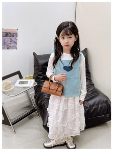 Detail view of stylish kids outfit featuring blue heart vest and lace tiered skirt