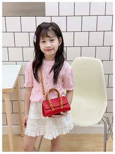 Detail of red faux leather kids handbag with brown handles and crossbody strap