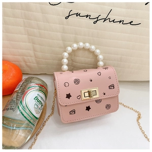 Dettaglio mini borsa rosa per bambini con manico di perle, chiusura d'oro e motivi cartoon