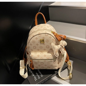 Detail of off-white mini backpack with brown letters pattern and cute animal charm