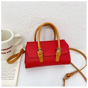 Detail of red pebbled leather girls handbag with brown handles and metal buckles