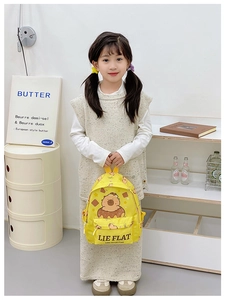 Close-up of kids yellow backpack with cute bear print and LIE FLAT text detail