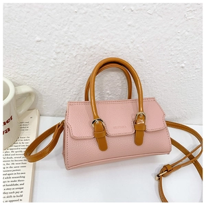 Detail of pink lychee leather texture and gold buckle on a stylish mini handbag