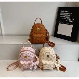 Detailed macro shot of three mini printed backpacks in brown, pink and white with bow charms