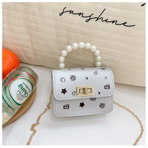 Dettaglio mini borsa argento bimba con manico di perle, catena oro e motivi a stella