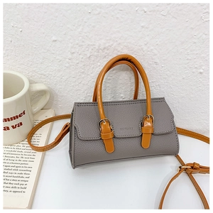 Detail of grey pebbled leather handbag with contrasting orange handles and magnetic clasp
