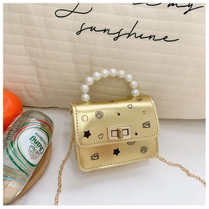 Dettaglio della mini borsa dorata con graffiti cartoon e manico di perle eleganti