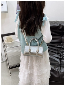 Silver metallic leather mini bag worn by a model in a stylish indoor setting