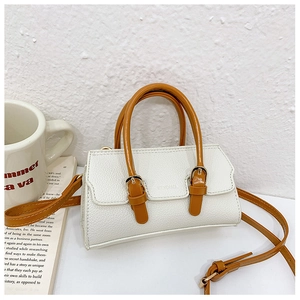 Detail of white pebbled leather kids handbag with caramel straps and gold metal buckles