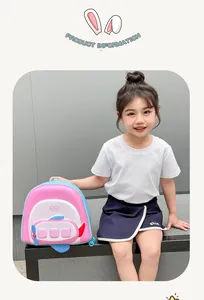 Pink airplane-shaped kids backpack shown on a child model in a bright outdoor setting