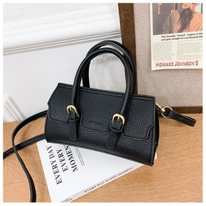 Black litchi grain mini handbag with gold buckles on white vintage prop books