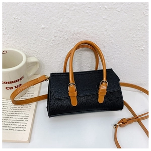 Detail of lychee textured leather mini bag with gold buckle and chic black-orange contrast