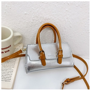 Detail view of silver textured girl's handbag with vibrant orange handle and adjustable strap