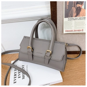 Detail of grey lychee leather handbag with golden buckles and adjustable shoulder strap