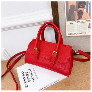 Detail of red pebbled leather child handbag with gold buckles and dual top handles