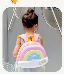 Pink children's backpack with cute 3D rainbow and bear relief detail in a lifestyle setting
