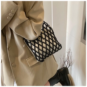 Close-up of black beaded mesh handbag with white satin lining and elegant top handle