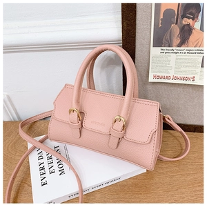Detailed macro view of pink litchi grain PU leather kids handbag with gold buckles