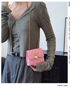Detailed view of pink quilted PU leather bag featuring a gold heart lock and chain strap