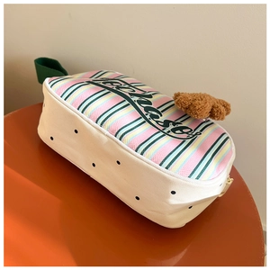 Détail d'un sac à main rayé coloré avec motif à pois et un joli pendentif ours en peluche